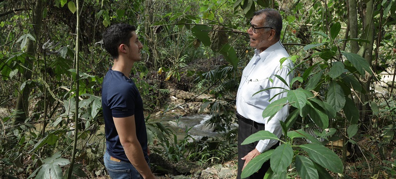 Imagen de profesor y estudiante dialogando en el bosque de la Universidad de Ibagué